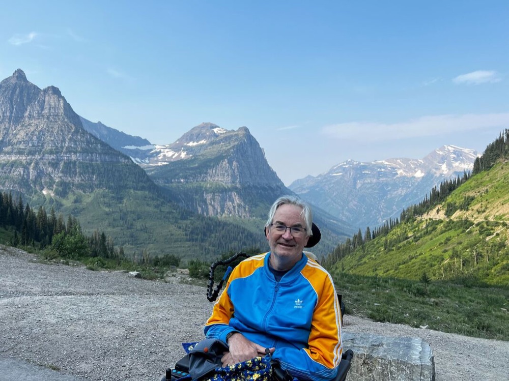 Community member in a wheelchair in front of mountains